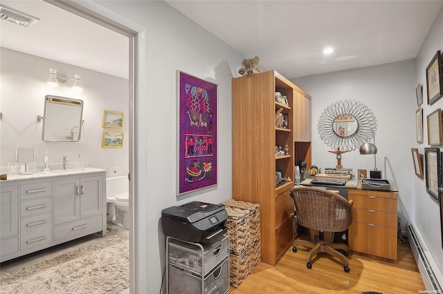 office with baseboard heating, sink, and light hardwood / wood-style floors