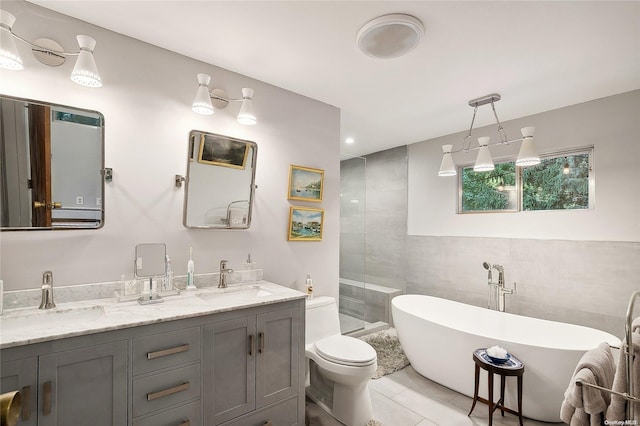 full bathroom with tile patterned floors, separate shower and tub, toilet, vanity, and tile walls