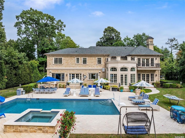 back of house featuring a lawn, french doors, a pool with hot tub, a balcony, and a patio area