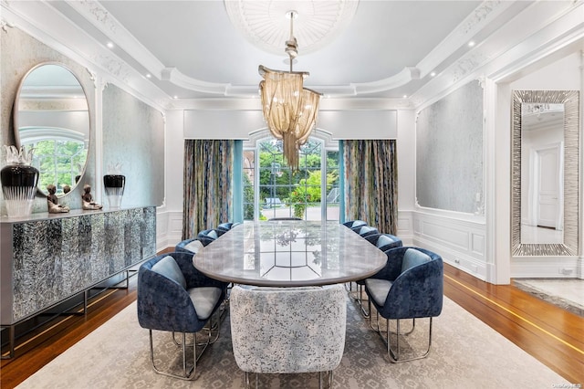 dining area with hardwood / wood-style flooring, a raised ceiling, crown molding, and a notable chandelier