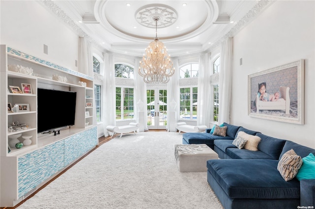 living room with french doors, a high ceiling, an inviting chandelier, hardwood / wood-style floors, and ornamental molding