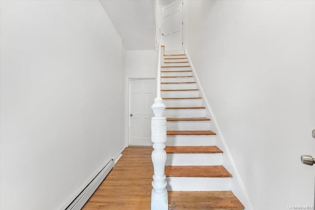 stairs with hardwood / wood-style floors and baseboard heating