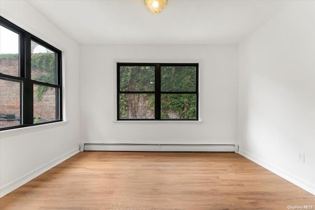 spare room with a baseboard radiator and light hardwood / wood-style flooring