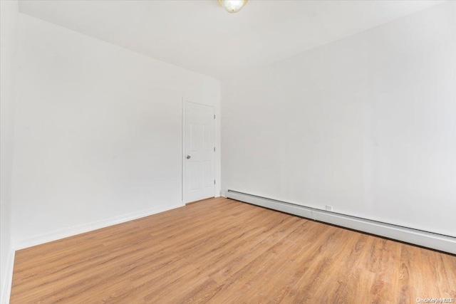 empty room featuring a baseboard heating unit and light hardwood / wood-style flooring