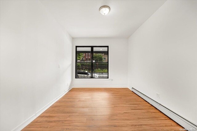 unfurnished room featuring light hardwood / wood-style flooring and a baseboard heating unit