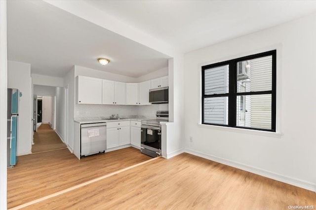 kitchen featuring backsplash, sink, light wood-type flooring, white cabinetry, and stainless steel appliances