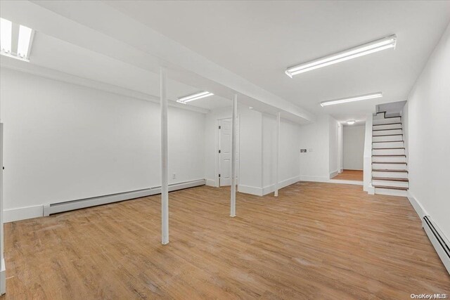 basement featuring light hardwood / wood-style flooring and baseboard heating