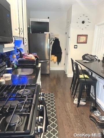 kitchen featuring stainless steel appliances, white cabinetry, and dark hardwood / wood-style floors