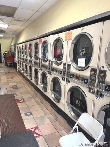 clothes washing area featuring independent washer and dryer, stacked washer and dryer, and tile patterned flooring