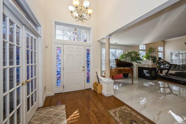 foyer entrance with a chandelier, decorative columns, and dark hardwood / wood-style floors