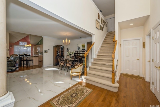 stairway with ornamental molding, wood-type flooring, and a notable chandelier