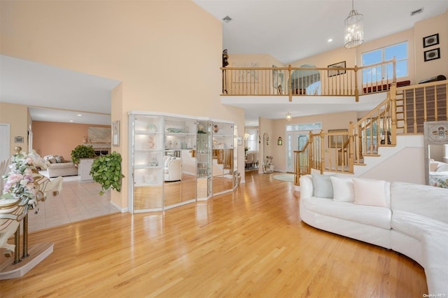 living room featuring hardwood / wood-style flooring, plenty of natural light, a high ceiling, and a chandelier