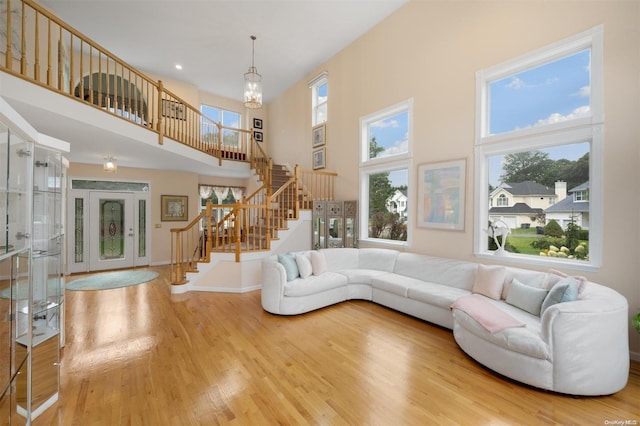 living room featuring wood-type flooring, a wealth of natural light, a notable chandelier, and a high ceiling