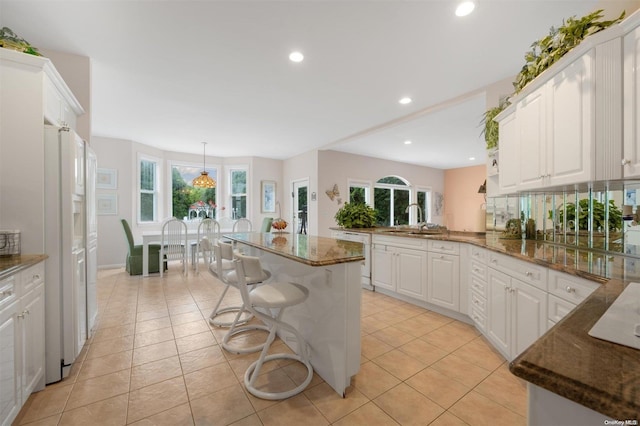 kitchen featuring white cabinets, a kitchen breakfast bar, kitchen peninsula, and a kitchen island