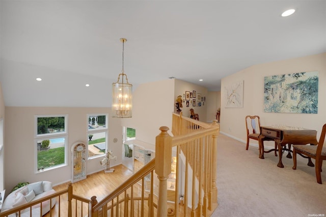 hall with light carpet, lofted ceiling, and an inviting chandelier