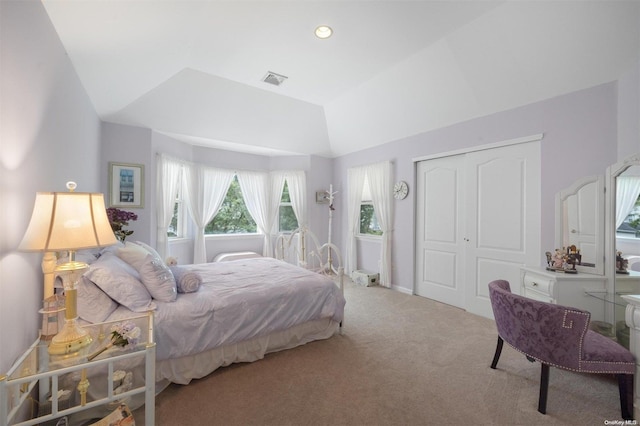 bedroom with light colored carpet, vaulted ceiling, and a closet