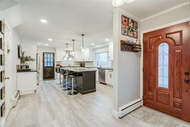 foyer entrance with light hardwood / wood-style flooring, baseboard heating, and ornamental molding