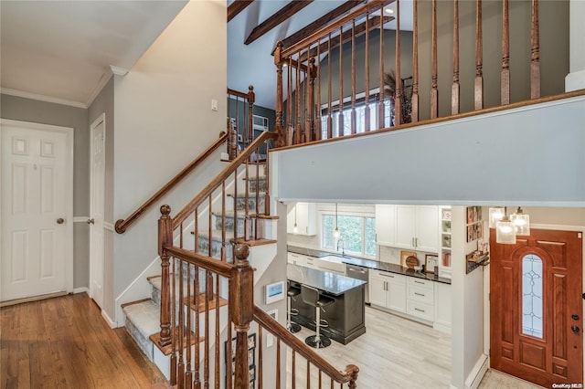 stairs with hardwood / wood-style floors and crown molding