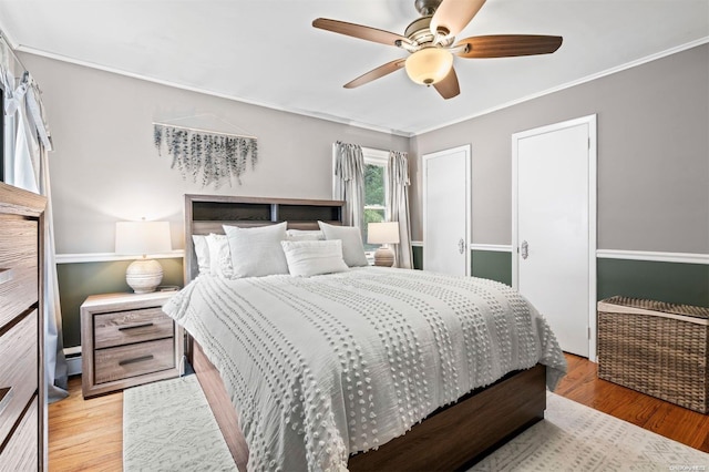 bedroom featuring ceiling fan, ornamental molding, and light wood-type flooring