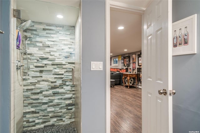 bathroom with tiled shower and hardwood / wood-style flooring