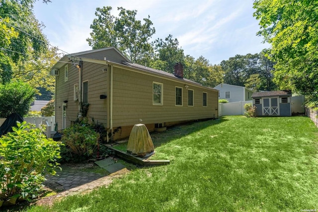 back of house with a lawn and a storage unit