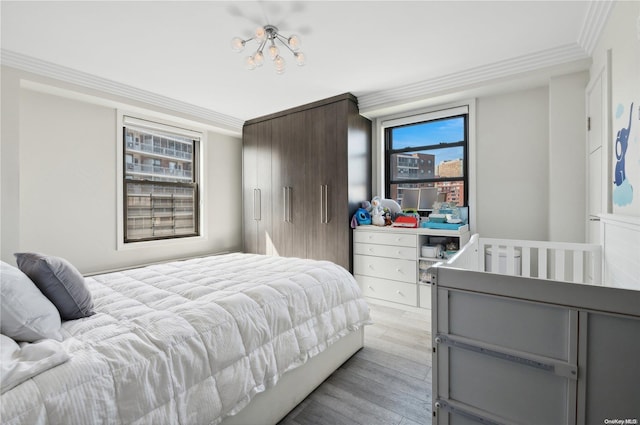 bedroom with light hardwood / wood-style flooring, crown molding, and a notable chandelier