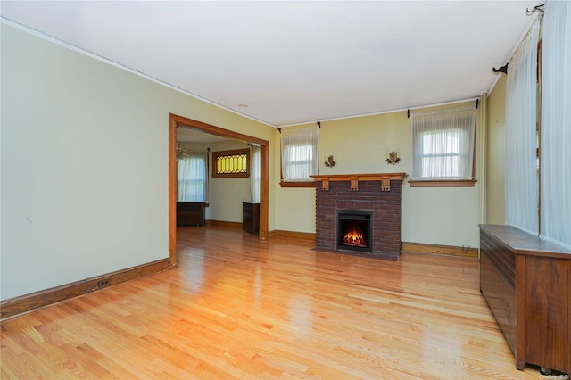 unfurnished living room featuring a fireplace, light wood-type flooring, and plenty of natural light