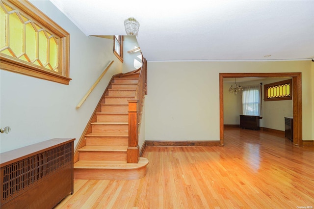 stairs featuring hardwood / wood-style flooring, a notable chandelier, and ornamental molding