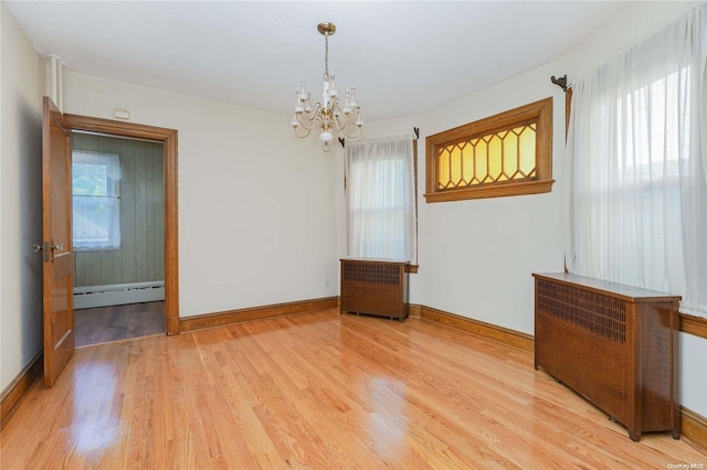 spare room with a healthy amount of sunlight, light hardwood / wood-style flooring, and a baseboard heating unit