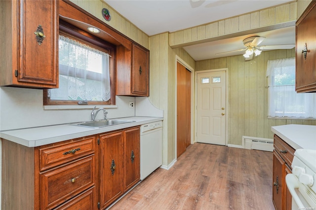 kitchen featuring white dishwasher, ceiling fan, sink, light hardwood / wood-style floors, and wood walls