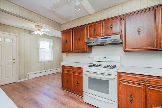 kitchen featuring wood walls, white range, ceiling fan, baseboard heating, and light hardwood / wood-style floors