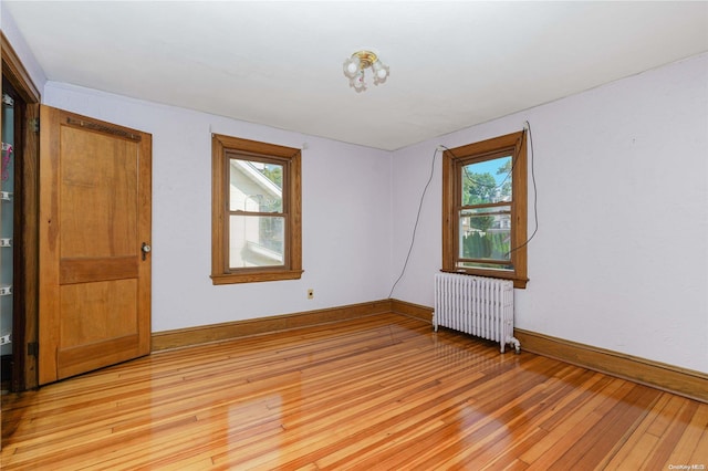 empty room featuring radiator heating unit, plenty of natural light, and light hardwood / wood-style flooring