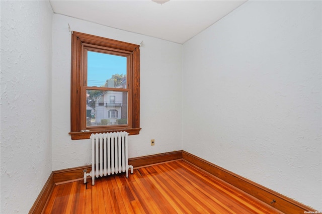 spare room with radiator heating unit, hardwood / wood-style flooring, and vaulted ceiling