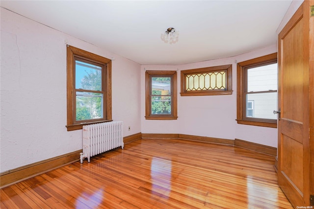 spare room featuring radiator heating unit, plenty of natural light, and light hardwood / wood-style flooring