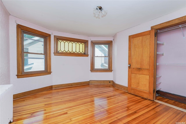 unfurnished room featuring radiator heating unit, plenty of natural light, and light wood-type flooring