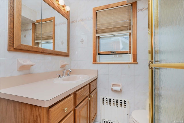 bathroom with radiator heating unit, vanity, toilet, and tile walls