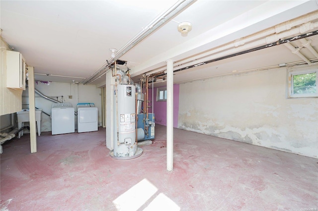 basement featuring separate washer and dryer, sink, and water heater