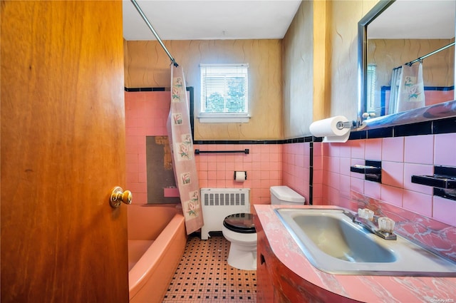 full bathroom featuring radiator, vanity, shower / tub combo with curtain, tile walls, and toilet