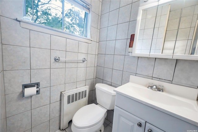 bathroom featuring vanity, toilet, tile walls, and radiator