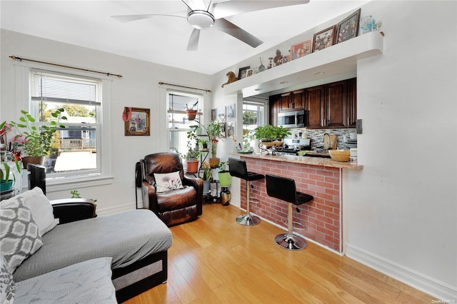 living room with a fireplace, light wood-type flooring, and ceiling fan