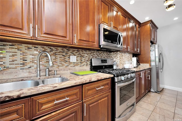 kitchen with backsplash, light stone countertops, sink, and appliances with stainless steel finishes