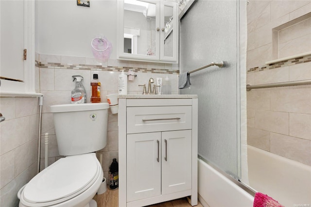 full bathroom featuring vanity, toilet, tile walls, and enclosed tub / shower combo