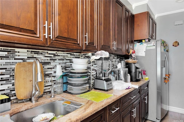 kitchen with tasteful backsplash, stainless steel refrigerator, crown molding, and sink