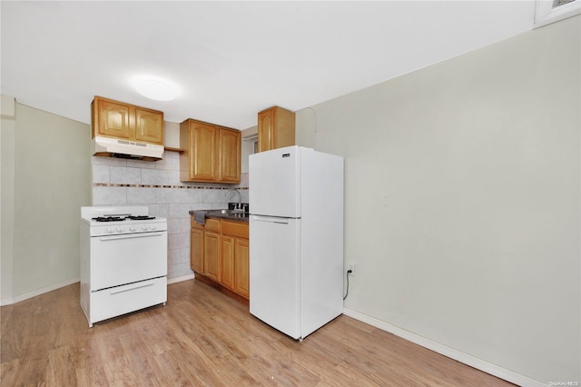 kitchen with white appliances, tasteful backsplash, light hardwood / wood-style flooring, and sink