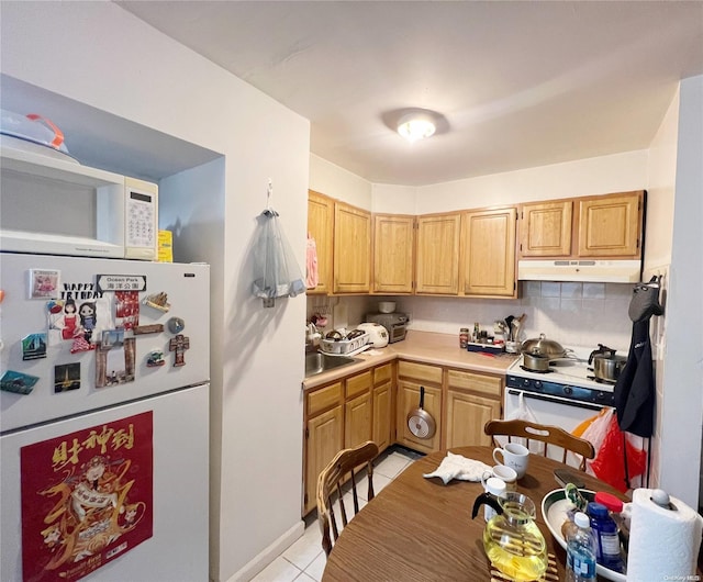 kitchen featuring white appliances, light tile patterned floors, and tasteful backsplash