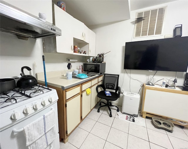 kitchen with white cabinets, light tile patterned flooring, white range with gas stovetop, and exhaust hood