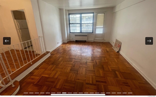 empty room featuring dark parquet flooring and radiator