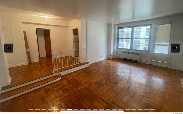 spare room with dark parquet flooring and radiator heating unit