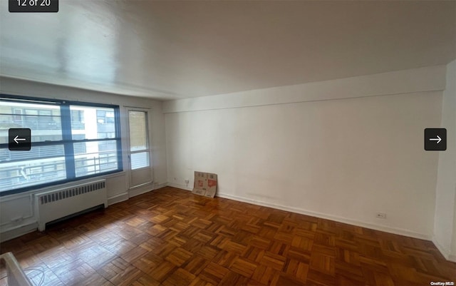 unfurnished room featuring radiator and dark parquet flooring