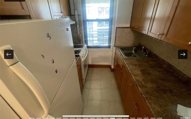 kitchen with decorative backsplash, sink, light tile patterned floors, and white appliances